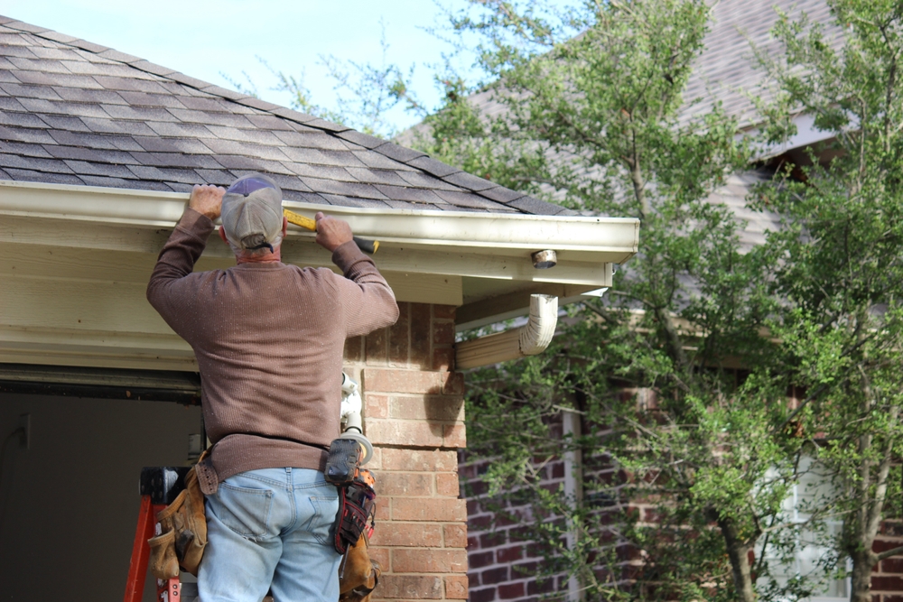 Installing,roof,gutters;,worker,attaching,aluminum,rain,gutter,and,down